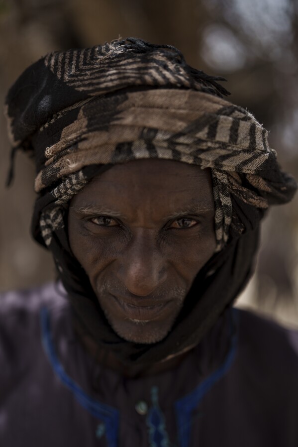 Amadou Djiby, 44, stands for a portrait at a local market near a water station known as Bem Bem, in the Matam region of Senegal, Wednesday, April. 19, 2023. Djiby explains that there are several difficulties working as a herder. The cattle are thirsty due to the lack of water, lack of good grassland, animal feed is expensive and when you have to sell them you bend to the realities of the prices. "Before it was better because there was more rain but now the rain is rare", he says. (AP Photo/Leo Correa)