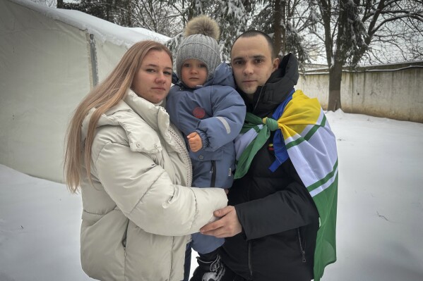 Kateryna Dmytryk, left, and husband Artem Dmytryk hold their son, Timur, after Artem was released from Russian captivity as a part of a prisoner swap in Kyiv, Ukraine, Feb. 9, 2024. (AP Photo/Vasilisa Stepanenko)