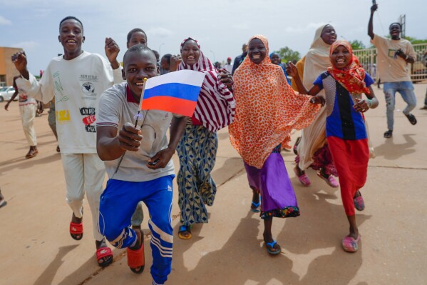 Supporters of Niger's ruling junta hold a Russian flag in Niamey, Niger, Sunday, Aug. 6, 2023. Nigeriens are bracing for a possible military intervention as time's run out for its new junta leaders to reinstate the country's ousted president. (AP Photo/Sam Mednick)