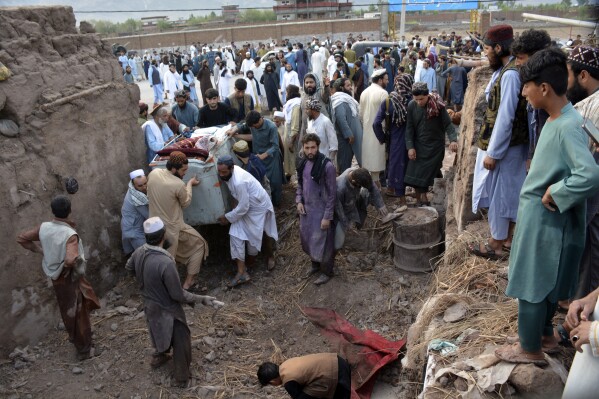 People gather to clear the rubble of a house partially damaged by landslide due to heavy rainfall in Surkhroad district of Jalalabad, Nangarhar province east of Kabul, Afghanistan, Monday, July 15, 2024. (AP Photo/Shafiullah Kakar)