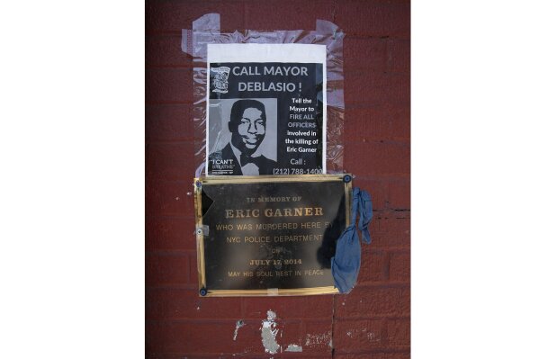 A sign and plaque are displayed on a wall, Tuesday, July 16, 2019, in the Staten Island borough of New York, at the sidewalk area where Eric Garner was apprehended by police in 2014. Federal prosecutors announced Tuesday, they will not bring charges against New York City police officer Daniel Pantaleo in the 2014 chokehold death of Garner. (AP Photo/Mark Lennihan)
