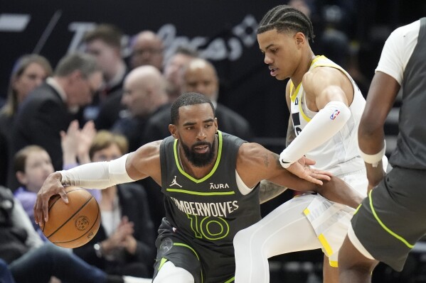 Minnesota Timberwolves guard Mike Conley (10) drives around Utah Jazz guard Keyonte George, right, during the first half of an NBA basketball game Saturday, March 16, 2024, in Salt Lake City. (AP Photo/Rick Bowmer)