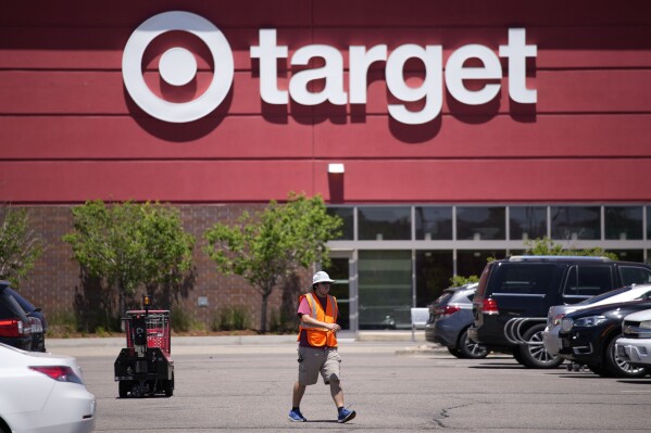 FILE - A worker collects shopping carts in the parking lot of a Target store June 9, 2021, in Highlands Ranch, Colo. Target says it's cutting prices on about 5,000 food, beverage and household essential items, becoming the latest company to shift its pricing strategy as consumers pay closer attention to how they spend their money amid inflation concerns.(AP Photo/David Zalubowski, File)