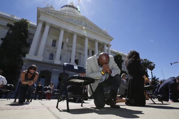 FILE - In this June 9, 2020, file photo, Assemblyman Mike Gipson, D-Carson, bows his head as he and other members of the California Legislature kneel to honor George Floyd at the Capitol in Sacramento, Calif. Lawmakers approved, Thursday, Sept. 9, 2021, Gipson's measure that would prohibit police from using techniques that create a substantial risk of what's known as "positional asphyxia."  (AP Photo/Rich Pedroncelli, File)