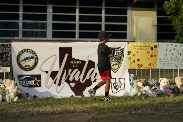 A boy walks along a memorial outside Robb Elementary School created to honor the victims killed in last week's school shooting, Friday, June 3, 2022, in Uvalde, Texas. (AP Photo/Eric Gay)