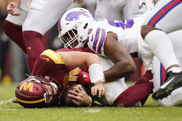 Washington Commanders quarterback Sam Howell (14) on the ground after being sacked by Buffalo Bills defensive end Greg Rousseau (50) during the second half of an NFL football game, Sunday, Sept. 24, 2023, in Landover, Md. (AP Photo/Evan Vucci)