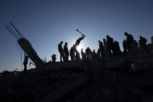 Palestinians search for bodies and survivors in the rubble of a house destroyed in an Israeli airstrike, in Rafah, southern Gaza Strip, Sunday, Jan. 7, 2024. (APPhoto/Fatima Shbair)