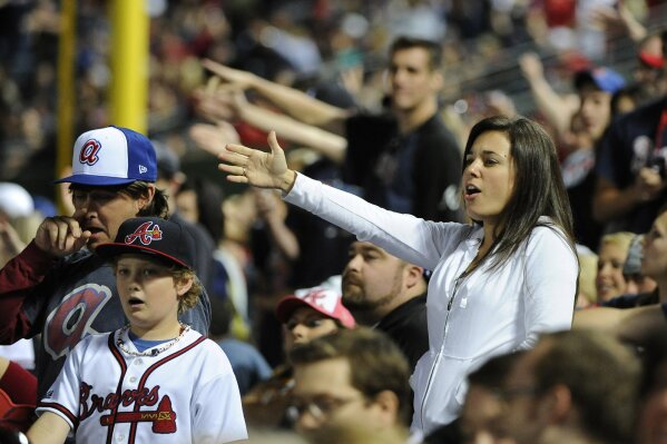 FILE - In this May 2, 2014, file photo, Atlanta Braves fans do the tomahawk chop during the ninth inning of a baseball game with the San Francisco Giants, in Atlanta. The Atlanta Braves say they have no plans to follow the lead of the NFL's Washington Redskins and change their team name. The team said in a letter to season ticket holders they are examining the fan experience, including the tomahawk chop chant, and have formed a "cultural working relationship" with the Eastern Band of the Cherokees in North Carolina. (AP Photo/David Tulis, File)