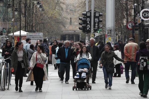 People walk through downtown Skopje, North Macedonia, on Wednesday, March 30, 2022. North Macedonia has lost nearly 10% of its population over the last two decades mostly due to emigration, statistics officials said on Wednesday, announcing the official results of a 2021 census. (AP Photo/Boris Grdanoski)