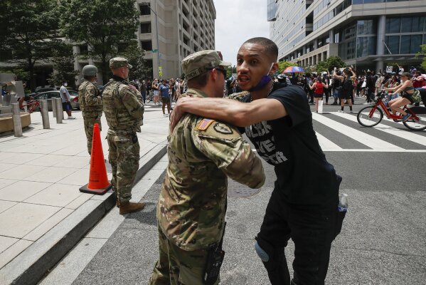 FILE - In this June 6, 2020, file photo, a demonstrator hugs a National Guard soldier during a protest  in Washington, over the death of George Floyd, a black man who was in police custody in Minneapolis. The National Guard has designated military police units in two states to serve as rapid reaction forces in order to be better prepared to respond quickly to civil unrest around the country, in the wake of the violent protests that rocked the nation’s capitol and several states this summer. (AP Photo/Alex Brandon, File)