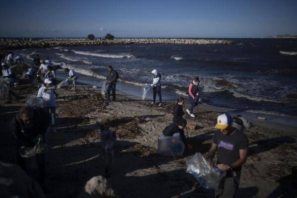 Volunteers clean a beach from trash that was washed up by a storm in Marseille, southern France, Oct. 6, 2021. (AP Photo/Daniel Cole)
