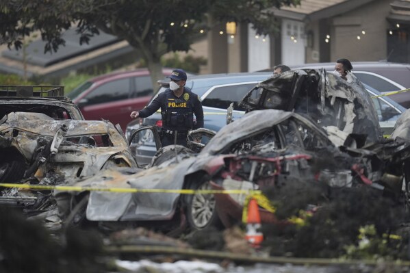 Authorities work the scene where a small plane crashed into a San Diego neighborhood, setting several homes on fire and forcing evacuations along several blocks early Thursday, May 22, 2025. (AP Photo/Gregory Bull)
