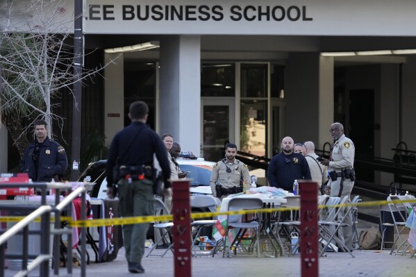 Las Vegas police stand near the scene of a shooting at the University of Nevada, Las Vegas, Thursday, Dec. 7, 2023, in Las Vegas. Terrified students and professors cowered in classrooms and dorms as a gunman roamed the floors of a campus building on Wednesday, killing several people and critically wounding another person before dying in a shootout with police. (AP Photo/John Locher)