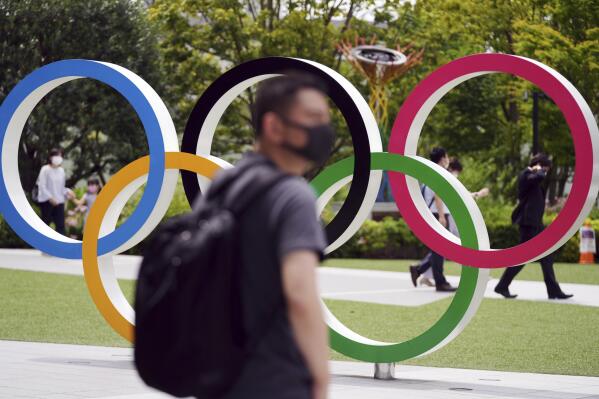 People walk near the Olympic Rings Wednesday, June 2, 2021, in Tokyo. Roads are being closed off around Tokyo Olympic venues including the new $1.4 billion National Stadium where the opening ceremony is set for July 23. (AP Photo/Eugene Hoshiko)