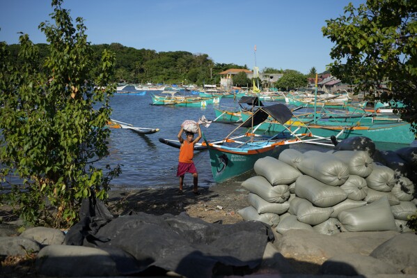 A resident brings down a sack from his boat at the coastal town of Santa Ana, Cagayan province, northern Philippines on Tuesday, May 7, 2024. The United States and the Philippines, which are longtime treaty allies, have identified the far-flung coastal town of Santa Ana in the northeastern tip of the Philippine mainland as one of nine mostly rural areas where rotating batches of American forces could encamp indefinitely and store their weapons and equipment within local military bases under the Enhanced Defense Cooperation Agreement, or EDCA. (AP Photo/Aaron Favila)