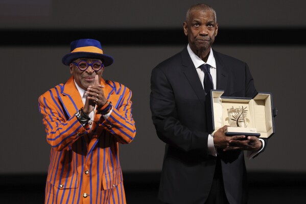 Actor Denzel Washington receives an Honorary Palme d'Or (Golden Palm) from director Spike Lee, left, ahead of the screening of the film "Highest 2 Lowest" at the 78th edition of the Cannes Film Festival in Cannes, southern France, Monday, May 19, 2025. (Sameer Al-Doumy, Pool via AP)