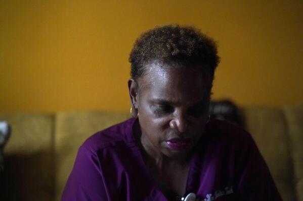 Karen Nix sits in her home before leaving for her evening work shift in New Orleans, Tuesday, Aug. 23, 2022. Nix tells her story of surviving hurricanes Katrina and Ida while living with cerebral palsy. (AP Photo/Gerald Herbert)