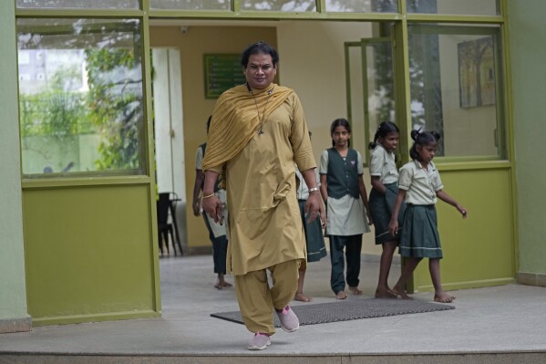 Preethi, a 38-year-old transgender woman who uses only her first name, walks out with students of Shishu Mandir, an organization which provided her an electric auto rickshaw to earn her livelihood, in Bengaluru, India, Monday, July 10, 2023. (AP Photo/Aijaz Rahi)