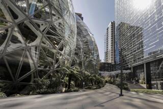 FILE - In this March 20, 2020, file photo, the Amazon campus outside the company headquarters in Seattle sits nearly deserted on an otherwise sunny and warm afternoon. Amazon said Monday, Oct. 11, 2021 it will allow many tech and corporate workers to continue working remotely indefinitely, as long as they can commute to the office when necessary. (AP Photo/Elaine Thompson, File)