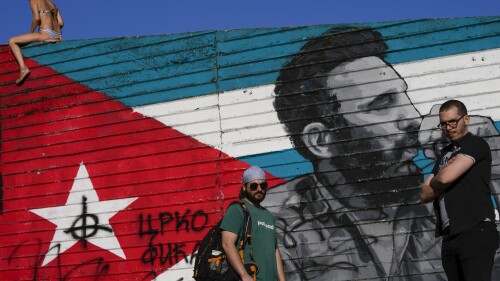 Fernando Almeyda Rodriguez, right, and Remy Hernandez, pose in front of a mural of late Cuban leader Fidel Castro, in Belgrade, Serbia, Saturday, July 8, 2023. Rodriguez and Hernandez were forced to flee Cuba in the aftermath of 2021 mass protests to avoid persecution for their activism. An unlikely migration route brought them to Serbia last year, where they found safety and sought political asylum. (AP Photo/Darko Vojinovic)