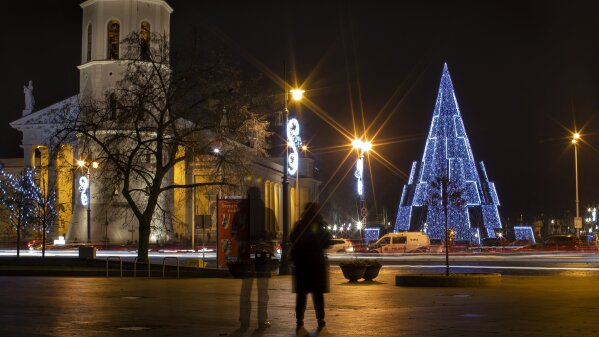 Visitors look at the Christmas tree in Cathedral Square in Vilnius, Lithuania, Saturday, Dec. 5, 2020. (AP Photo/Mindaugas Kulbis)