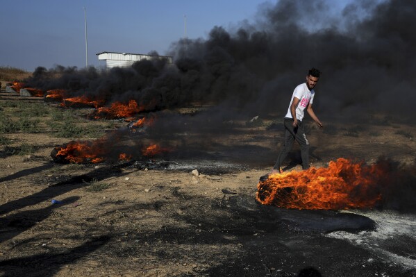 A Palestinian protester burns tires during clashes with Israeli security forces along the frontier with Israel, east of Gaza City, Tuesday, Sept. 19, 2023. (AP Photo/Adel Hana)