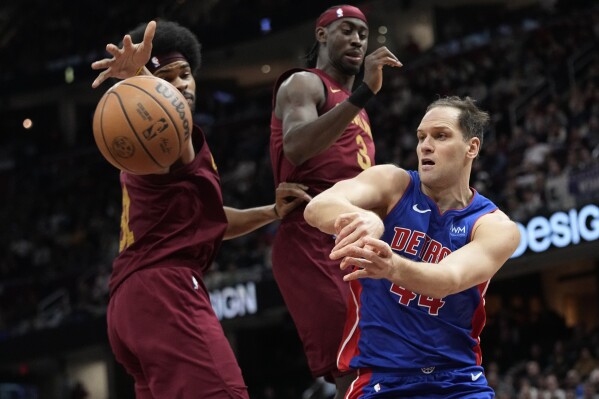 Detroit Pistons forward Bojan Bogdanovic, right, passes around Cleveland Cavaliers center Jarrett Allen, left, in the second half of an NBA basketball game, Wednesday, Jan. 31, 2024, in Cleveland. (AP Photo/Sue Ogrocki)