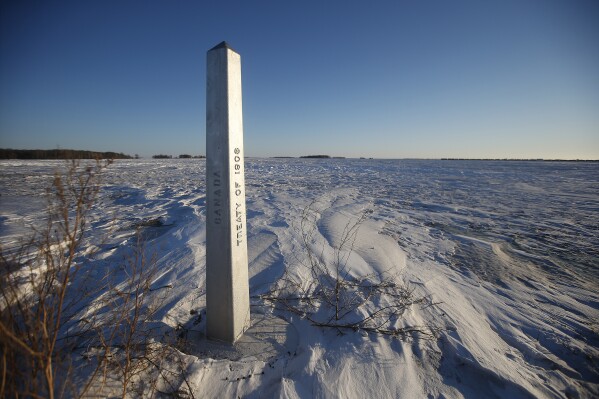 FILE - A border marker, between the United States and Canada is shown just outside of Emerson, Manitoba, on Thursday, Jan. 20, 2022. A man accused of helping to lead a human smuggling operation that was implicated in the deaths of a family of four from India — who froze while trying to walk across the Canada-U.S. border during a blizzard in 2022 — had been warned about dangerous weather conditions before the group set out on the trip, court papers alleged. (John Woods/The Canadian Press via AP, File)
