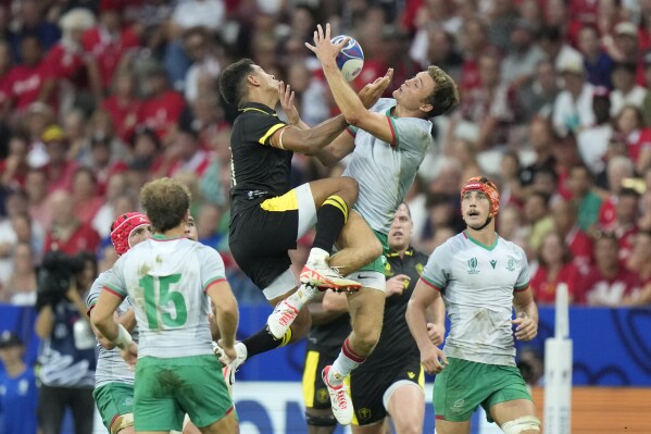 Wales' Rio Dyer, left leaps for the ball with Portugal's Jeronimo Portela during the Rugby World Cup Pool C match between Wales and Portugal in the Stade de Nice, in Nice, France Saturday, Sept. 16, 2023. (AP Photo/Pavel Golovkin)