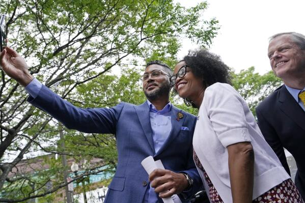 Imari Paris Jeffries, left, executive director of King Boston, holds a cell phone as he takes a selfie with Boston's acting Mayor Kim Janey and Mass. Gov. Charlie Baker, far right, in Boston's Nubian Square during a Juneteenth commemoration, Friday, June 18, 2021, in Boston. (AP Photo/Elise Amendola)