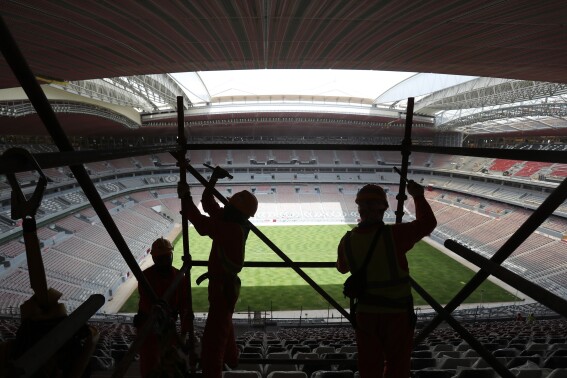 FILE - Laborers remove scaffolding at the Al Bayt stadium in Al Khor, Qatar, about 50 kilometers (30 miles) north of Doha, Monday, April 29, 2019. FIFA is under pressure to publish a long-awaited review into compensation for workers who helped deliver the 2022 World Cup in Qatar. (AP Photo/Kamran Jebreili, File)