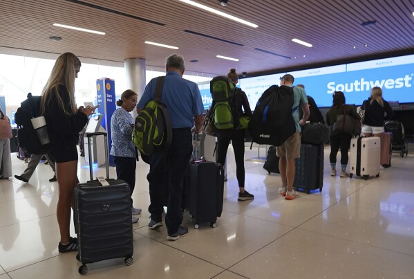 Travelers queue up at the check-in counters for their flights on Southwest Airlines in the main terminal of Denver International Airport Friday, May 23, 2025. (AP Photo/David Zalubowski)