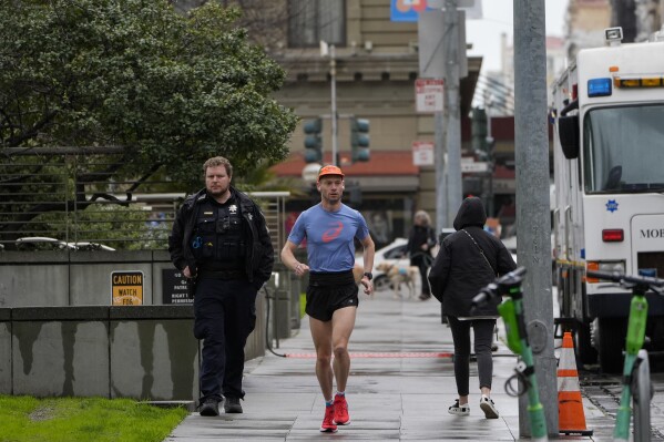 A San Francisco Police Department officer walks around Union Square, Friday, March 1, 2024, in San Francisco. Voters in San Francisco will weigh in on a pair of public safety measures on the Tuesday, March 5, ballot that reflect frustration over crime and drug use in the politically liberal city, including a proposal to compel treatment for adults who receive cash welfare benefits if they are using illegal drugs. The other ballot measure would expand police powers, granting city officers greater leeway to pursue suspects in vehicles, authorize police use of drones and surveillance cameras and reduce paperwork requirements including in use-of-force cases. (AP Photo/Godofredo A. Vásquez)