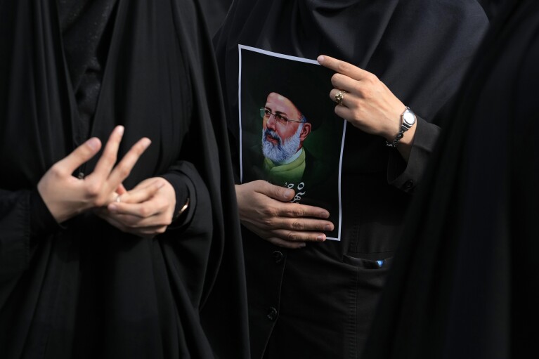 An Iranian woman holds a poster of President Ebrahim Raisi during a mourning ceremony for him at Vali-e-Asr square in downtown Tehran, Iran, Monday, May 20, 2024. Iranian President Raisi and the country's foreign minister were found dead Monday hours after their helicopter crashed in fog, leaving the Islamic Republic without two key leaders as extraordinary tensions grip the wider Middle East. (AP Photo/Vahid Salemi)