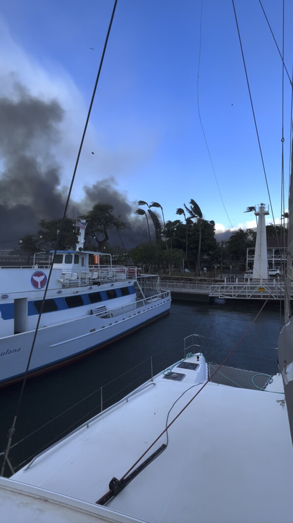 In this photo provided by Brantin Stevens, smoke fill the air from wild fires at Lahaina harbor on Tuesday, Aug. 8, 2023 in Hawaii. Fire was widespread in Lahaina Town, including on Front Street, a popular shopping and dining area, County of Maui spokesperson Mahina Martin said by phone early Wednesday. Traffic has been very heavy as people try to evacuate the area, and officials asked people who weren’t in an evacuation area to shelter in place to avoid adding to the traffic, she said. (Brantin Stevens via AP)