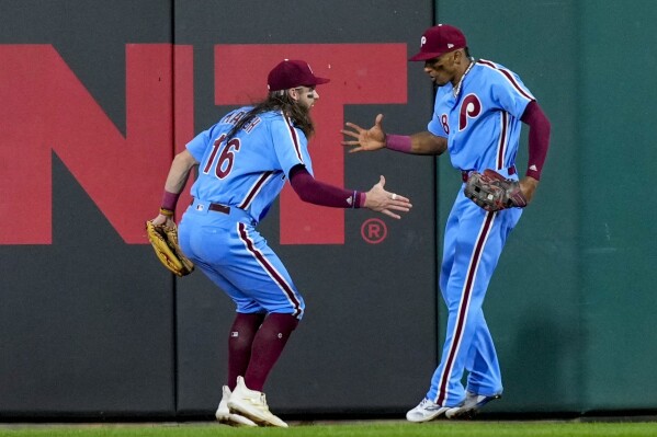 Philadelphia Phillies' Johan Rojas is congratulated by Brandon Marsh (16) after catching a long fly ball hit by Atlanta Braves' Ronald Acuna Jr. during the seventh inning of Game 4 of a baseball NL Division Series Thursday, Oct. 12, 2023, in Philadelphia. (AP Photo/Matt Rourke)