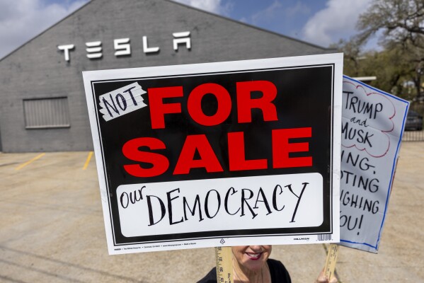 Protesters outside a Tesla Service Center on Tchoupitoulas Street in New Orleans express their issues with Elon Musk and President Donald Trump on Friday, March 14, 2025. 