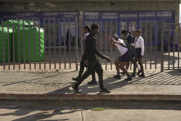 Three high school girls make their way through the city centre on their way to school in Dundee, South Africa, Friday, Oct. 27, 2023. Thousands of children in South Africa's poorest and most remote rural communities still face a miles-long walk to school, nearly 30 years after the country ushered in democratic change. (AP Photo/ Sebabatso Mosamo)