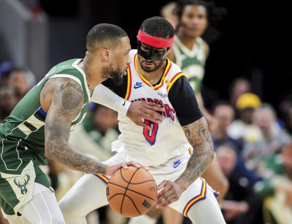 Golden State Warriors' Gary Payton II (0) defends against Milwaukee Bucks' Damian Lillard (0) in the first half of an NBA basketball game in San Francisco, on Tuesday, March 18, 2025. (Carlos Avila Gonzalez/San Francisco Chronicle via AP)