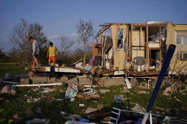 Aiden Locobon, left, and Rogelio Paredes look through the remnants of their family's home destroyed by Hurricane Ida, Saturday, Sept. 4, 2021, in Dulac, La. (AP Photo/John Locher)