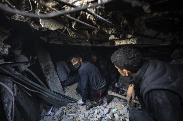 Palestinians search for bodies and survivors in the rubble of a residential building destroyed in an Israeli airstrike, in Rafah, southern Gaza Strip, Friday, Dec. 15, 2023. (AP Photo/Fatima Shbair)