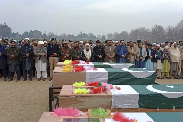 Officials and local residents offer funeral prayers of police officers, who were killed in the roadside bombing, in Khar, Pakistan, Monday, Jan. 8, 2024. A roadside bomb exploded Monday near a van carrying police assigned to protect workers in an anti-polio immunization campaign in restive northwestern Pakistan, killing and wounding officers and others, officials said. (AP Photo/Anwarullah Khan)