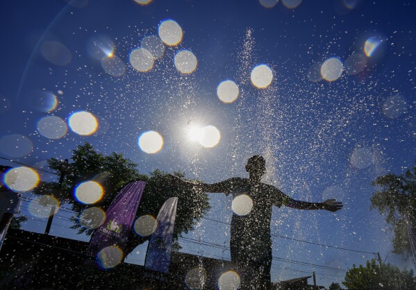 Un joven se refresca en un parque acuático público en un caluroso día de verano en Santiago, Chile, el miércoles 31 de enero de 2024. Durante el verano se instalan docenas de parques acuáticos públicos como este en toda la ciudad para ayudar a los residentes a refrescarse.  (Foto AP/Esteban Félix)