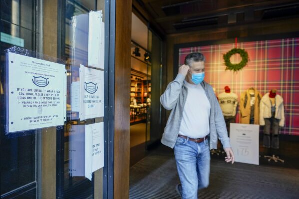 A Black Friday shopper adjusts his face mask as he leaves the Abercrombie & Fitch store along Fifth Avenue, Friday, Nov. 27, 2020, in New York. (AP Photo/Mary Altaffer)
