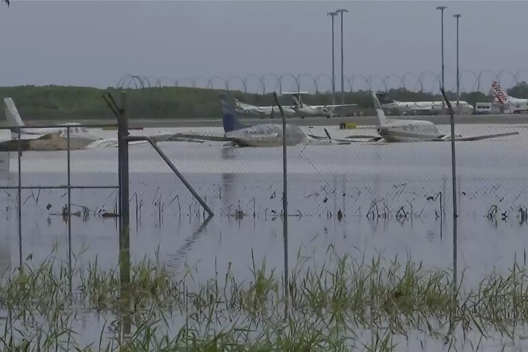 This image from a video, shows partially-submerged small planes at Cairns Airport in Cairns, Australia Monday, Dec. 18, 2023. More than 300 people were rescued overnight from floodwaters in northeast Australia, with dozens of residents clinging to roofs, officials said on Monday. (Australian Broadcasting Corp. via AP)