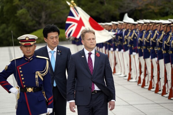 Britain's Defense Minister Grant Shapps, right, with Japanese Defense Minister Minoru Kihara, center, reviews an honor guard ahead of a bilateral meeting at the defense ministry Tuesday, Nov. 7, 2023, in Tokyo. (AP Photo/Eugene Hoshiko, Pool)