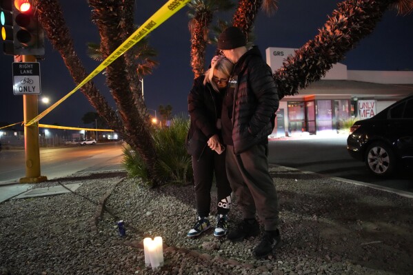 Sean Hathcock, right, kisses Michelle Ashley after the two left candles for victims of a shooting at the University of Nevada, Las Vegas, Wednesday, Dec. 6, 2023, in Las Vegas. The two graduated from the school and live nearby. (APPhoto/John Locher)