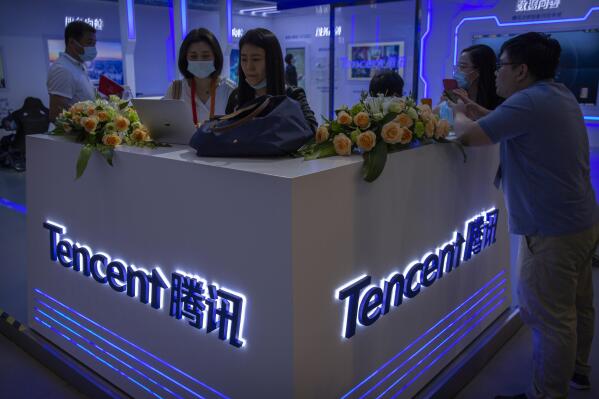 In this Sept. 5, 2020, photo, visitors gather at a display booth for Chinese technology firm Tencent at the China International Fair for Trade in Services (CIFTIS) in Beijing. Chinese financial regulators have summoned 13 companies engaged in online finance services, including Tencent and Bytedance, and told them to strengthen anti-monopoly measures. (AP Photo/Mark Schiefelbein)