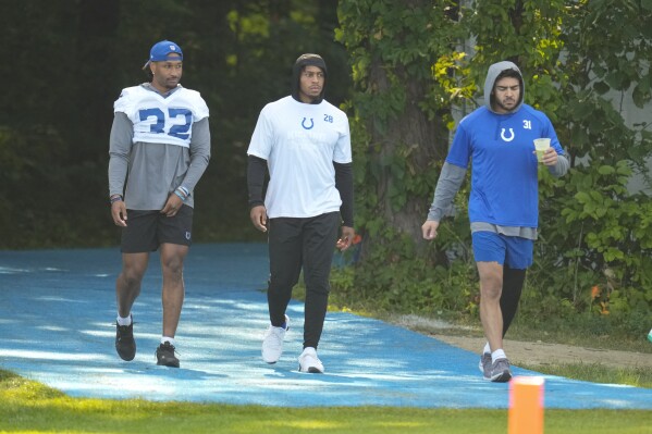 Indianapolis Colts players not participating in practice, left to right, safety Julian Blackmon, running back Jonathan Taylor and safety Daniel Scott walk to the field during practice at the NFL team's football training camp in Westfield, Ind., Tuesday, Aug. 1, 2023. (AP Photo/Michael Conroy)