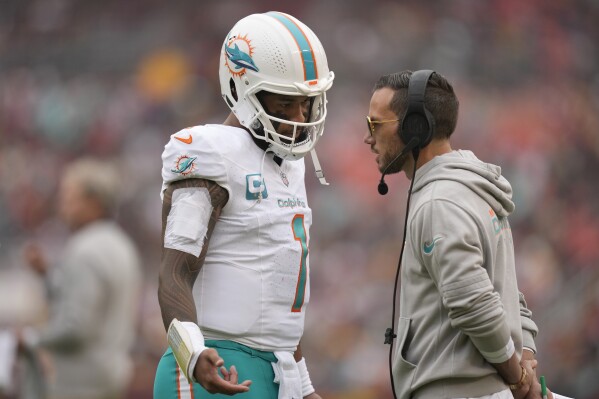 Miami Dolphins quarterback Tua Tagovailoa (1) talks with head coach Mike McDaniel during the first half of an NFL football game against the Washington Commanders Sunday, Dec. 3, 2023, in Landover, Md. (AP Photo/Alex Brandon)